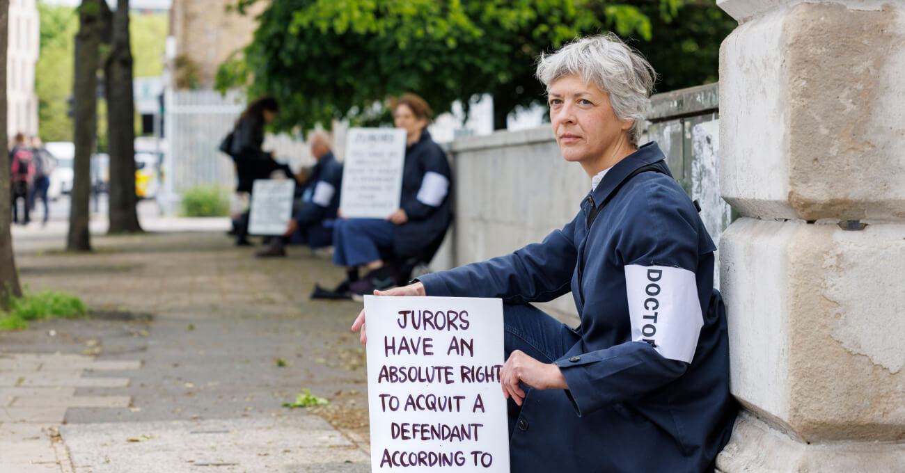 A line of people sitting and holding signs outside Isleworth Crown Court